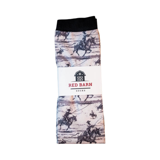 Folded sock with cowboy pattern on a wooden surface, featuring the Red Barn Socks brand.