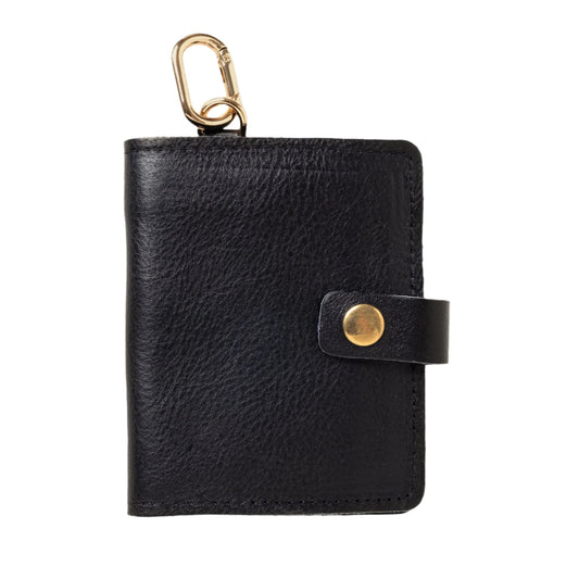 Black leather key pouch with gold clasp and button on a beige background