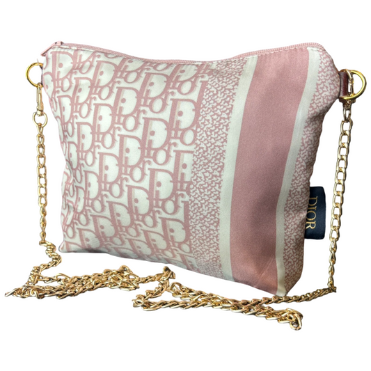 Pink handbag with gold chain strap and Dior logo on a white background